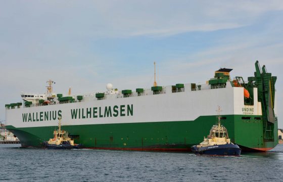 Large green and white vehicles carrier being pushed by tugboats into Fremantle Port